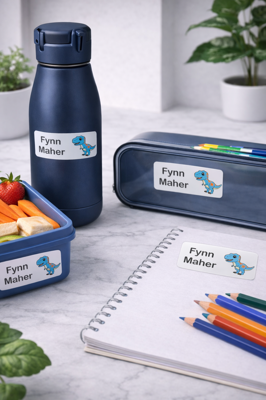 Navy blue water bottle, lunch box, and pencil case with personalized labels on a light gray surface.